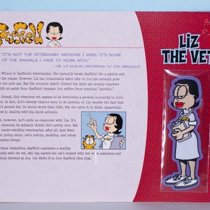 May include: A Garfield comic strip featuring Liz the Vet, a cartoon character in a white uniform with a clipboard. The text reads "Liz The Vet" in bold, white letters on a red background. The comic strip is on a white background.