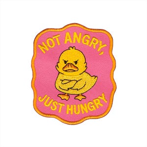 May include: Embroidered patch with a yellow duck, arms crossed, looking cross. The patch reads "NOT ANGRY, JUST HUNGRY" in yellow on a pink background with a gold border. Ideal for customising clothing or bags. The patch is suitable for jackets, bags, or other fabric items.