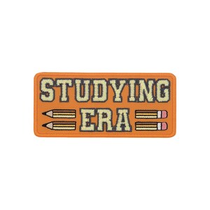 Peut inclure: Un écusson rectangulaire orange avec les mots "STUDYING ERA" en police de caractères crème et carrée. Deux crayons encadrent le mot "ERA". Les crayons sont marron avec des pointes crème et des gommes roses.