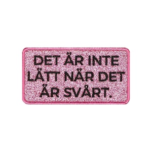 Könnte beinhalten: Rosa Glitzer-Aufbügel-Patch mit schwarzem Text, der "DET ÄR INTE LÄTT NÄR DET ÄR SVÅRT." lautet.