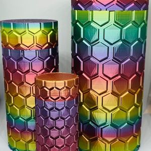 May include: Three iridescent cylindrical containers with a honeycomb pattern. The containers are different sizes and have a rainbow gradient of colors.