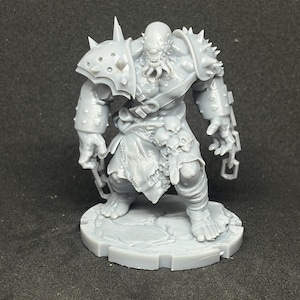 May include: A gray, cyclops-like monster figurine with spiked shoulder armor, a tattered loincloth, and chains. The figure stands on a circular base, showcasing intricate details and a menacing pose, perfect for tabletop gaming or display.