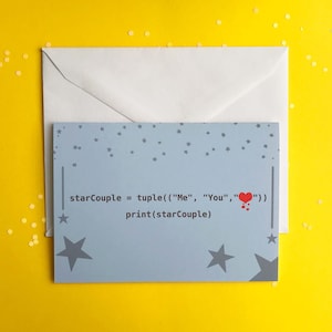 May include: A greeting card with a light blue background featuring a star pattern and the text "starCouple = tuple(("Me", "You", ":heart:")) print(starCouple)". A white envelope is behind the card, with yellow confetti scattered around.