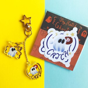 May include: A gold star keychain with two ghost-themed charms and a sticker sheet are set against a yellow and blue backdrop. The charms and stickers feature a cartoon ghost with baseball elements and the text "Try Catch!"