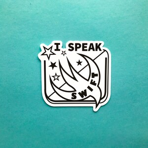 May include: A white sticker with black text and graphics on a teal background. The sticker reads "I SPEAK SWIFT" with a stylized bird graphic. Stars and a square frame surround the text and graphic.
