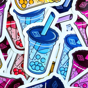 May include: A close-up of several colorful stickers featuring bubble tea with tapioca pearls. The stickers have different designs and colors, including blue, pink, purple, and yellow. Some stickers have text on them, including "PS" and "XD".