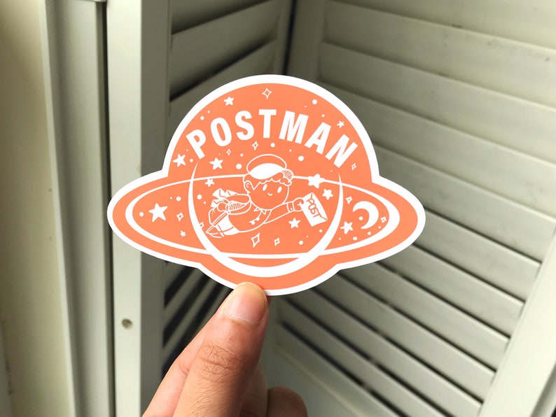 K&ouml;nnte beinhalten: Ein pfirsichfarbener Aufkleber mit einem wei&szlig;en Umriss eines Comic-Charakters, der mit einem Brief in der Hand durch den Weltraum fliegt. Der Aufkleber sagt "POSTMAN" in einem wei&szlig;en Kreis mit wei&szlig;en Sternen.