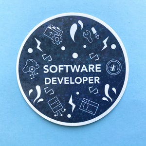 Może przedstawiać: Okrągła naklejka z ciemnoniebieskim tłem i białymi ilustracjami ikon związanych z komputerami. Tekst "SOFTWARE DEVELOPER" jest biały, ze stylizowaną czcionką. Naklejka ma białą obw&oacute;dkę i jest umieszczona na jasnoniebieskim tle.
