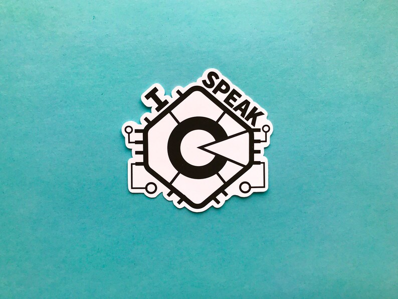 May include: A white sticker featuring a black graphic design and the words "I SPEAK". The design is a stylized circuit board with a central circular element and a pie-shaped wedge. The sticker is on a teal background.