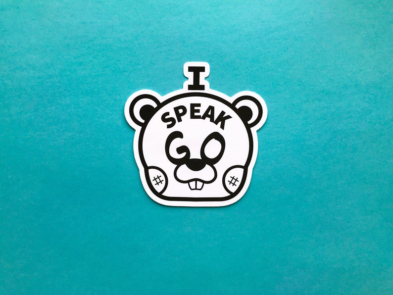 May include: A white sticker with a black outline of a cartoon bear face. The bear has the text "I SPEAK GO" in black letters. The sticker is on a teal background.