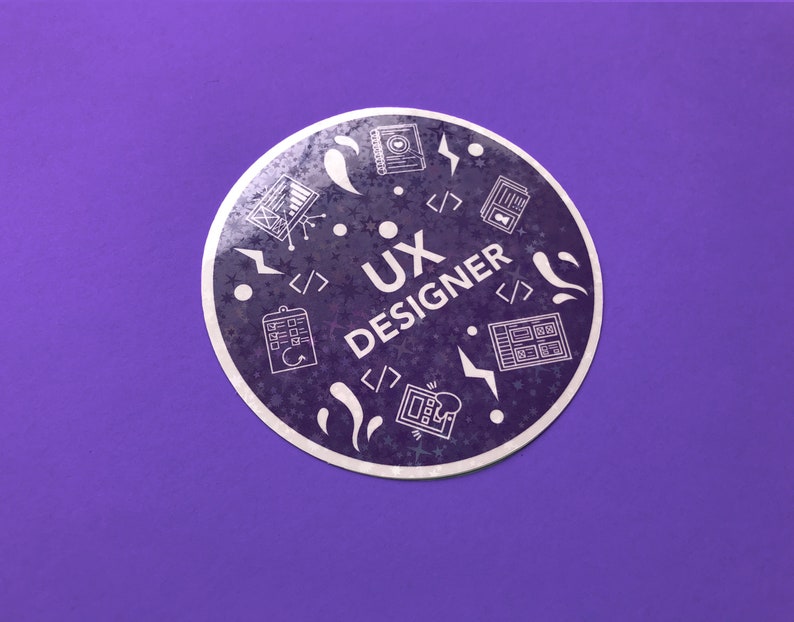 Op de afbeelding: Een ronde sticker met een paarse achtergrond en een wit ontwerp. De sticker zegt "UX Designer" en bevat pictogrammen die gerelateerd zijn aan user experience design, zoals een computerscherm, een notitieblok en een gloeilamp.