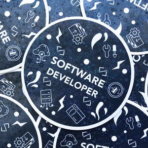 May include: Circular stickers with a dark blue background and white text and graphics. The stickers say "SOFTWARE DEVELOPER" and feature icons of code, clouds, and tools. The stickers have a white border and a holographic effect.
