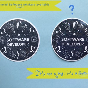 Może przedstawiać: Dwie okrągłe naklejki z ciemnym tłem i białą grafiką, w tym błyskawice, chmury i symbole kodu. Tekst "SOFTWARE DEVELOPER" znajduje się na środku. Naklejki są na jasnoniebieskiej powierzchni. Tekst brzmi "It's not a bug, it's a feature!"