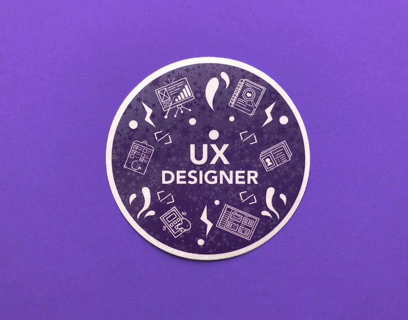 Op de afbeelding: Een paarse cirkel met witte pictogrammen en de tekst "UX DESIGNER" in het midden. De pictogrammen omvatten een kalender, een website, een notitieboekje, een telefoon en een gebruikersprofiel.