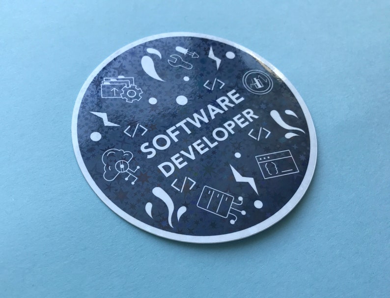 Może przedstawiać: Okrągła naklejka z granatowym tłem i białymi ilustracjami symboli i narzędzi kodowania. Tekst "SOFTWARE DEVELOPER" jest biały, z białą obw&oacute;dką. Naklejka znajduje się na jasnoniebieskiej powierzchni.