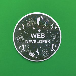 Pode incluir: Um autocolante redondo com fundo verde e design preto e prateado. O autocolante diz "WEB DEVELOPER" em texto branco. O design inclui &iacute;cones de laptop, l&acirc;mpada e s&iacute;mbolos de c&oacute;digo.