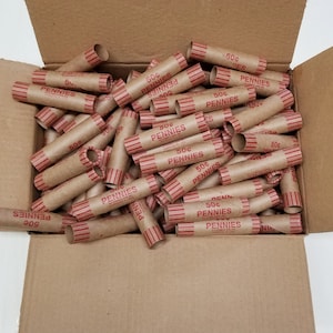 May include: A cardboard box filled with brown paper coin wrappers. Each wrapper is labeled "50¢ PENNIES".