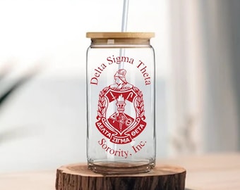 May include: A clear glass tumbler with a bamboo lid and a red and white Delta Sigma Theta Sorority, Inc. logo. The tumbler has a straw.