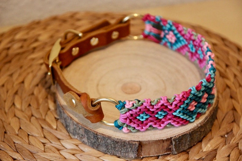 Peut inclure: Un collier de chien en cuir marron avec une boucle en m&eacute;tal dor&eacute; et deux anneaux. Le collier est d&eacute;cor&eacute; d'une bande tiss&eacute;e color&eacute;e dans des tons de rose, vert et bleu.