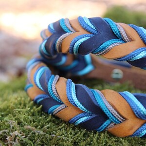 May include: A braided leather dog collar with blue, grey, and brown accents. The collar is braided with a rope-like texture.