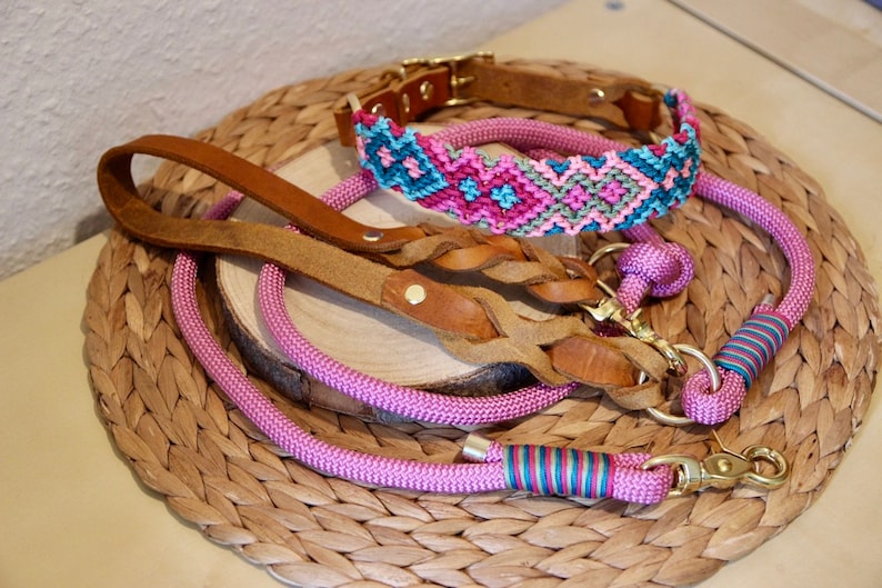 Peut inclure: Un ensemble de trois colliers et laisses pour chien en rose, marron et bleu. Les colliers et les laisses sont faits de diff&eacute;rents mat&eacute;riaux, dont le cuir, la corde et le tissu tiss&eacute;. Les colliers ont des fermoirs en m&eacute;tal dor&eacute;.