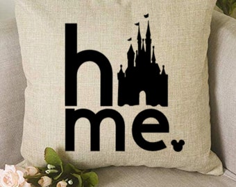 May include: A beige throw pillow with a black silhouette of a castle and the text "home" with a Mickey Mouse icon.