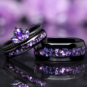 May include: Two black wedding bands with purple gemstones. The top band features a crown design with a large purple gemstone in the center. The bottom band has a scattered design of smaller purple gemstones.