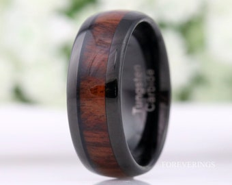 Op de afbeelding: Een zwarte ring van wolfraamcarbide met een bruine houten inlay en de woorden "Tungsten Carbide" gegraveerd aan de zijkant.