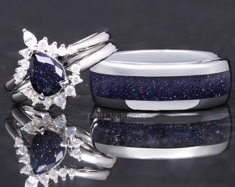 May include: A matching wedding ring set. The woman's ring features a pear-shaped, dark blue gemstone surrounded by small, clear stones. The man's ring has a dark blue, speckled band. Both rings are silver-colored. The word "FOREVERRINGS" is at the bottom.