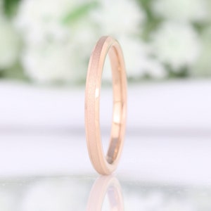 May include: A rose gold wedding band with a brushed finish and a beveled edge.