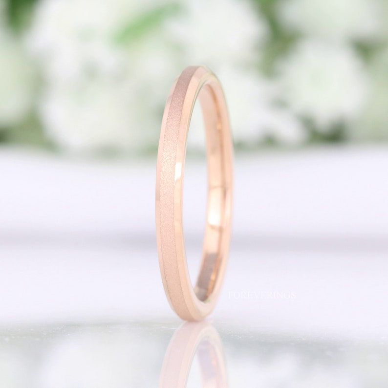 May include: A rose gold wedding band with a brushed finish and a beveled edge.