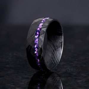 May include: A black carbon fiber ring with a purple glitter inlay. The ring is a simple band with a smooth finish.