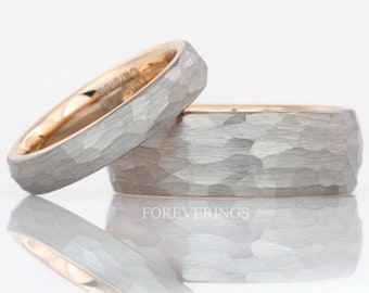 May include: Two wedding bands with a textured, hammered finish. The rings are silver-gray on the outside with a gold interior. The word "FOREVERINGS" is printed on the surface below the rings.