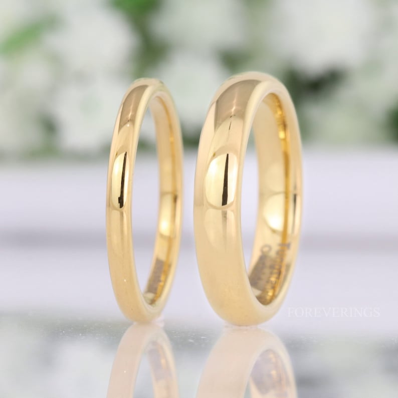 Men's and women's 2mm and 4mm gold tungsten rings standing side by side to compare widths