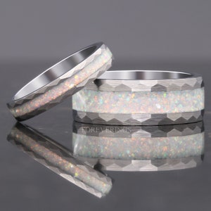 May include: Two silver rings with a textured, geometric design. The rings feature a band of white opal with iridescent flecks. The word "FOREVERRINGS" is visible on the larger ring.