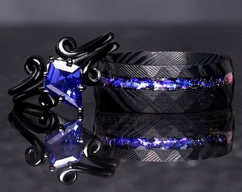 Puede incluir: Un par de alianzas de boda negras con una piedra preciosa azul. La banda de la izquierda tiene un diseño decorativo y la banda de la derecha tiene una incrustación azul y morada.