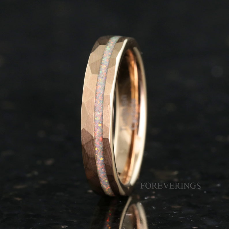 May include: A rose gold tungsten carbide ring with a hammered finish and a thin opal inlay.