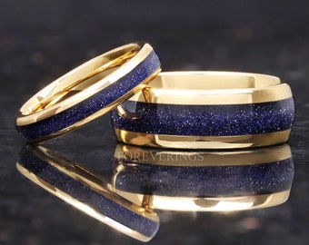 May include: Two gold wedding bands with a blue glitter inlay. The bands are stacked on top of each other.