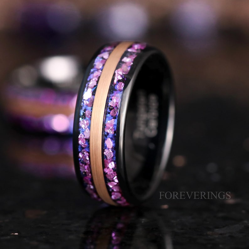 May include: A black tungsten carbide ring with a rose gold inlay and purple glitter embedded in the black band. The ring is engraved with the text "FOREVERINGS".