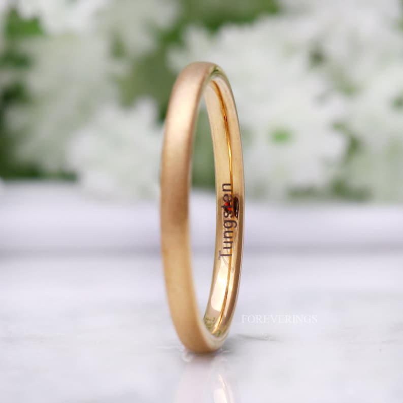 May include: A gold-colored tungsten ring with a brushed finish. The inscription "Tungsten" is engraved on the inside of the band.