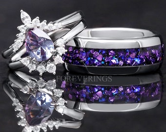 May include: A pair of wedding bands with a purple and silver design. The engagement ring features a pear-shaped amethyst gemstone surrounded by smaller diamonds. The wedding band has a silver band with a purple glitter inlay. The text "FOREVERINGS" is visible on the band.