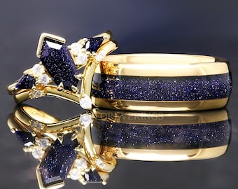 May include: A pair of gold rings. One ring features a cluster of dark blue, geometric-cut stones and small diamonds. The other ring has a wide band of dark blue, glittery material set in gold. The word "FOREVERRINGS" is visible on the ring.