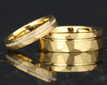 May include: Two gold wedding bands. One band has a hammered finish and the other has a white opal inlay.