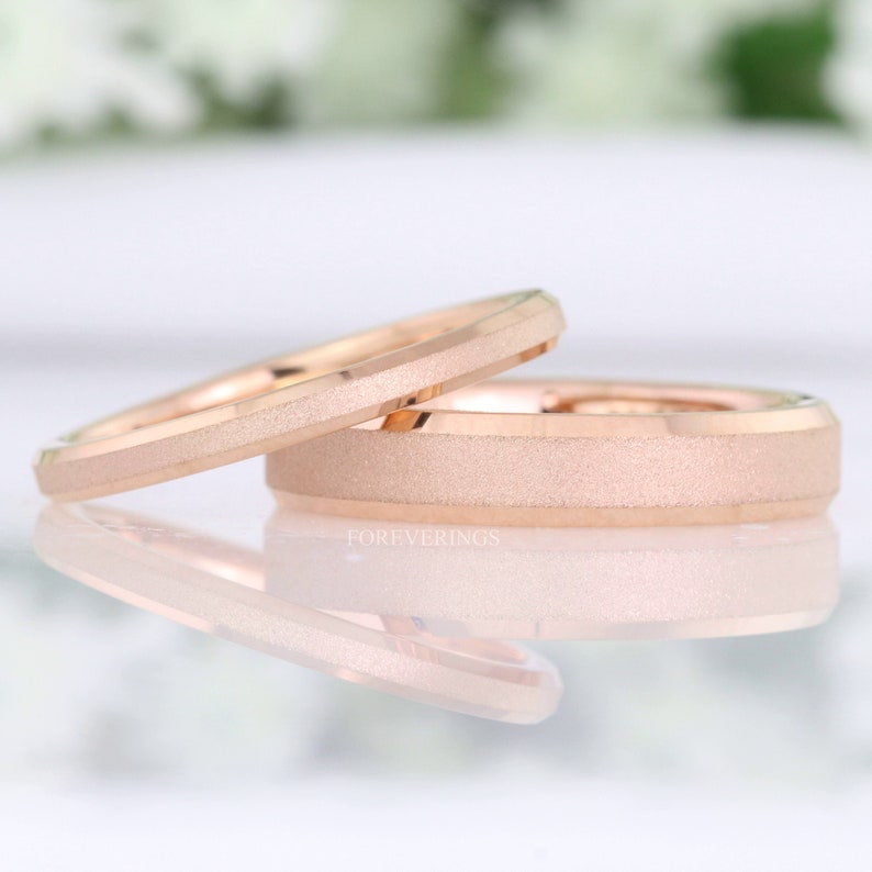 May include: Two rose gold wedding bands with a brushed finish. The bands are stacked on top of each other. The text "FOREVERINGS" is visible on the bottom band.
