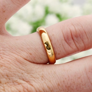 4mm gold tungsten band worn on a finger, close-up of the polished dome