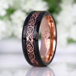 May include: A black tungsten carbide ring with a rose gold Celtic knot design. The ring has a beveled edge and a polished finish.