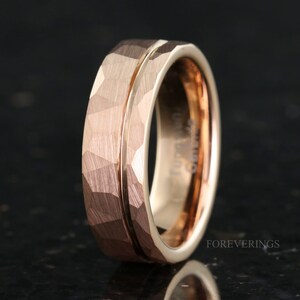 May include: A rose gold tungsten carbide ring with a hammered finish and a polished groove. The ring is a classic style and is perfect for a wedding band or an engagement ring.