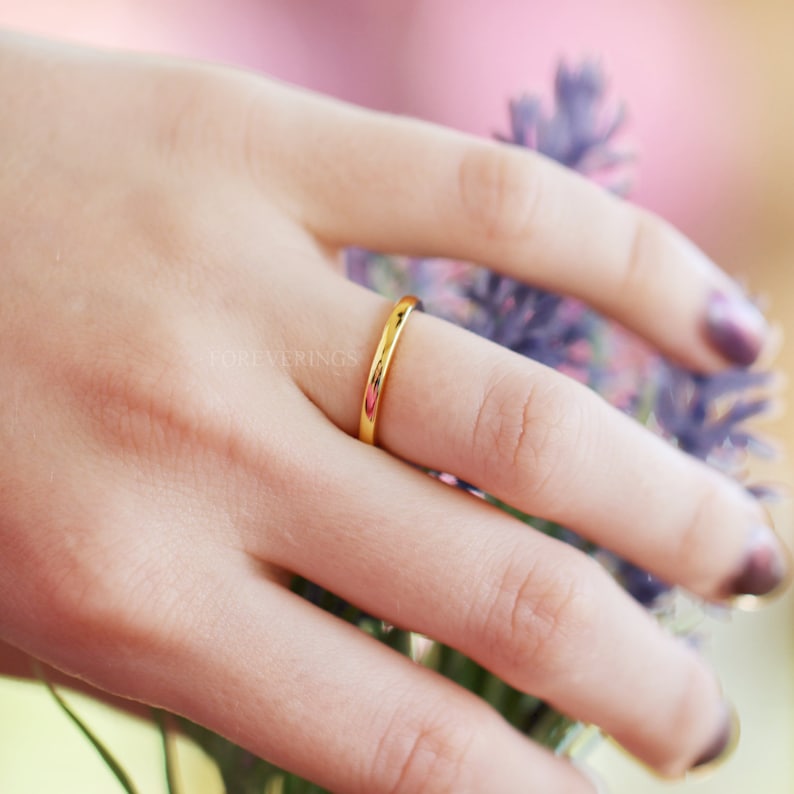 Women's 2mm gold tungsten wedding band worn on a hand