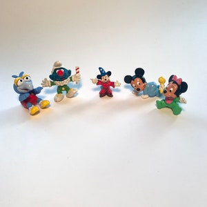May include: A set of five small plastic figurines. The figurines are of various characters, including a blue bird, a clown, a wizard, and Mickey Mouse and Minnie Mouse. The figurines are all in different poses and have bright colors.