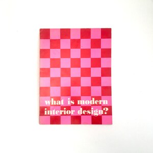 Puede incluir: Una portada de libro vintage con un patrón de tablero de ajedrez rosa y rojo. El título "what is modern interior design?" está impreso en blanco. El libro es rectangular y tiene un aspecto ligeramente desgastado.